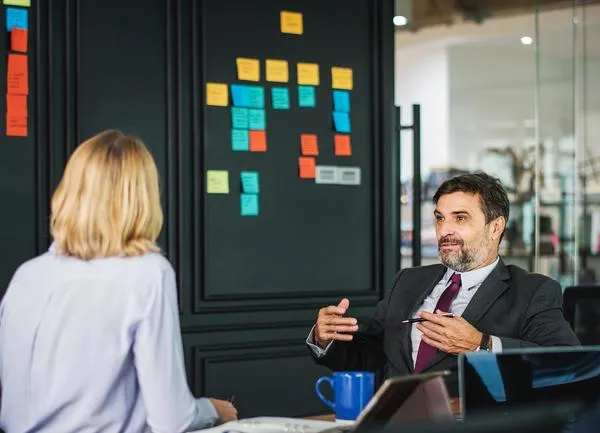 Un dirigeant et une collaboratrice en tenue professionnelle discutent