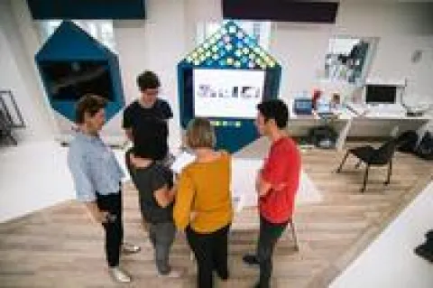 visuel article KPMG Un groupe de personnes se tient autour d'une table et discute.
